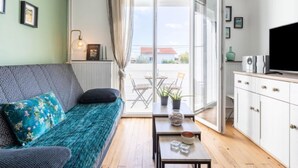 Ein modernes Wohnzimmer mit einer Couch, einem Couchtisch, einem Fernseher und Blick ins Freie.