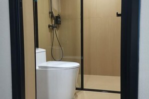 A small, enclosed shower area with a toilet and a showerhead. - Yunji Hotel (Ziyuan)