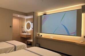 A hotel room with two beds, a large mirror, a vanity with a sink, and a wall-mounted TV. - Yunji Hotel (Ziyuan)