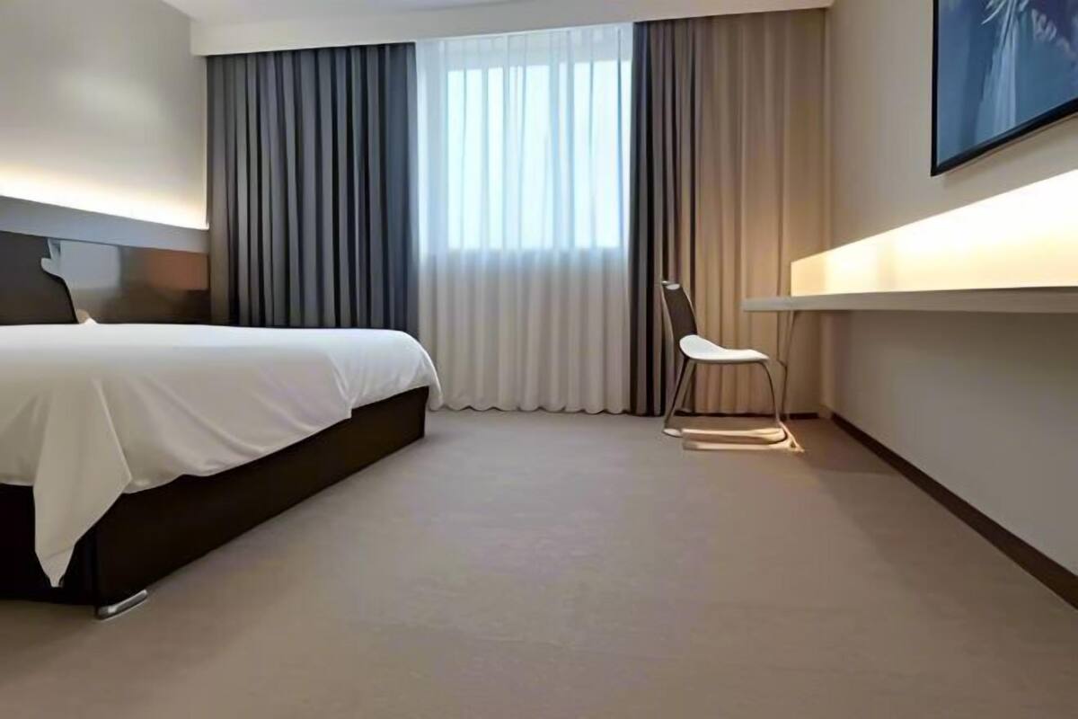 Una habitación de hotel moderna con una cama grande, un escritorio y una silla.