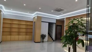 Un moderno vestíbulo de hotel con un diseño limpio y minimalista, que cuenta con una escalera central, un mostrador de recepción y una gran planta en maceta.