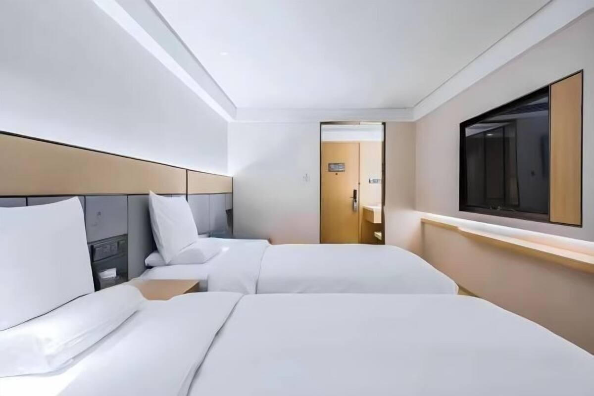 Una habitación de hotel con dos camas, un televisor y una puerta que da a un baño.