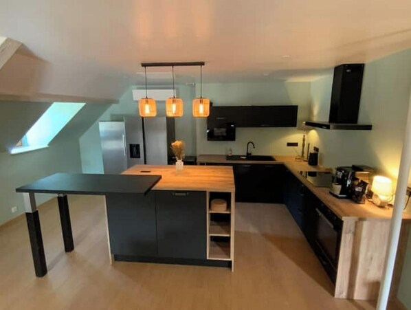 A modern kitchen with a central island, pendant lighting, and a skylight.