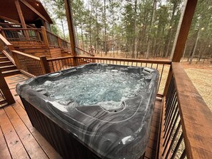Un jacuzzi en una terraza de madera con vistas a un bosque.