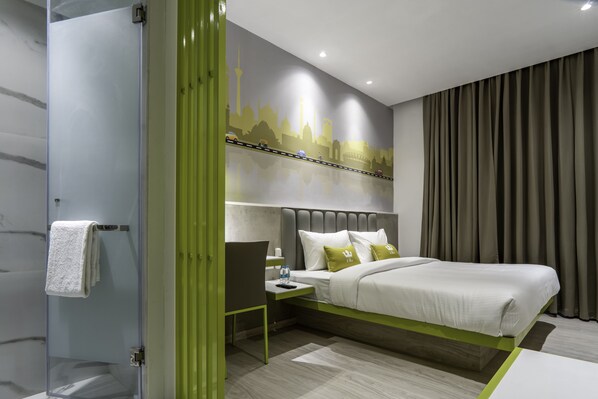 Una moderna camera d'hotel con un letto, un comodino e uno spazio doccia.