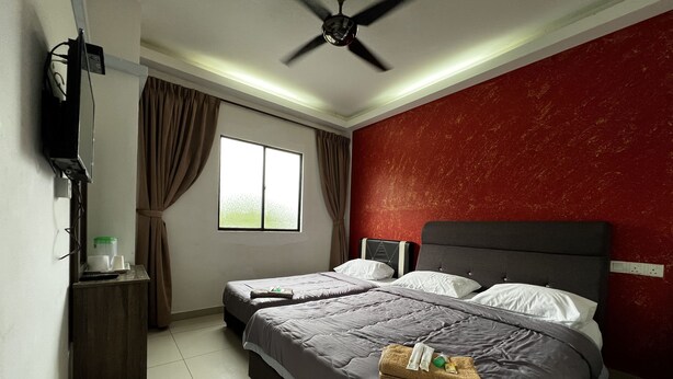 Quarto de hotel com cama, escrivaninha, ventoinha no teto e janela com cortinas.
