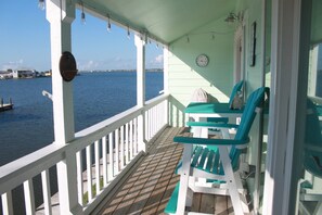 A covered porch with a view of the water, a clock, and two chairs. - Spectacular Key Allegro setting in Rockport (Rockport)