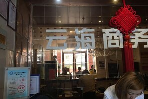 A restaurant interior with tables and chairs, a large red decorative hanging, and a sign with Chinese characters. - Yunhai Business Hotel (Ma'anshan)