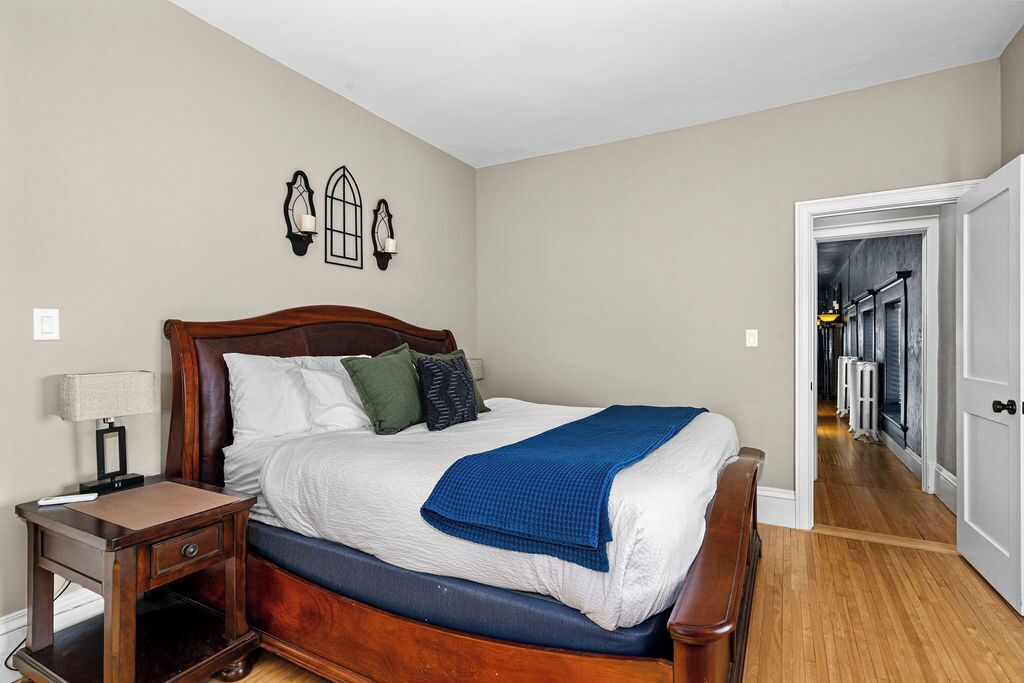 Quarto com cama de madeira, mesa de cabeceira e abajur.