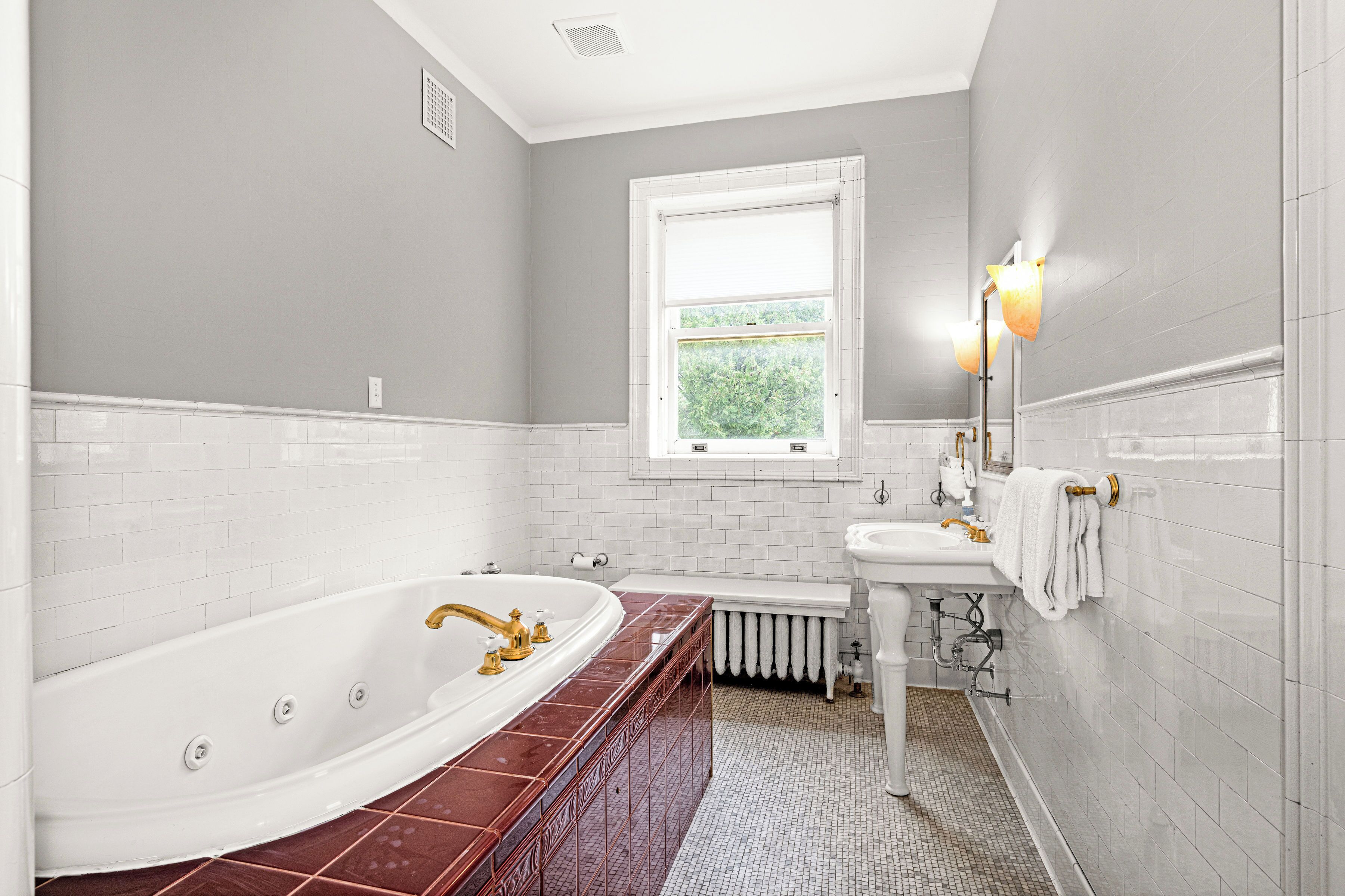 A bathroom with a large bathtub, a sink, and a window.