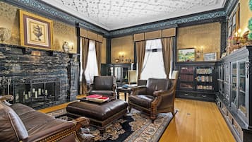 A formal room with leather furniture, a fireplace, and a bookshelf.
