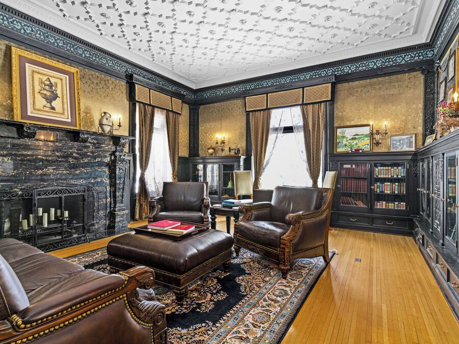 A formal room with leather furniture, a fireplace, and a bookshelf.