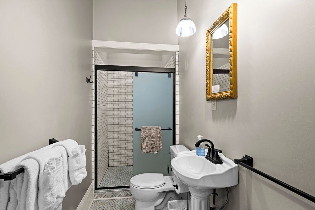 A bathroom with a toilet, sink, and a shower area with a glass door.