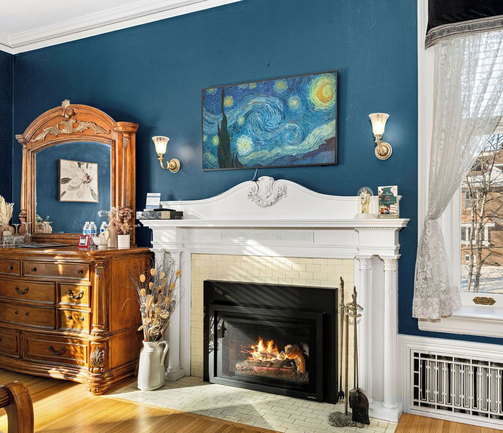Een kamer met een open haard, een groot schilderij en een dressoir.
