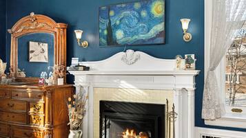 Een kamer met een open haard, een groot schilderij en een dressoir.