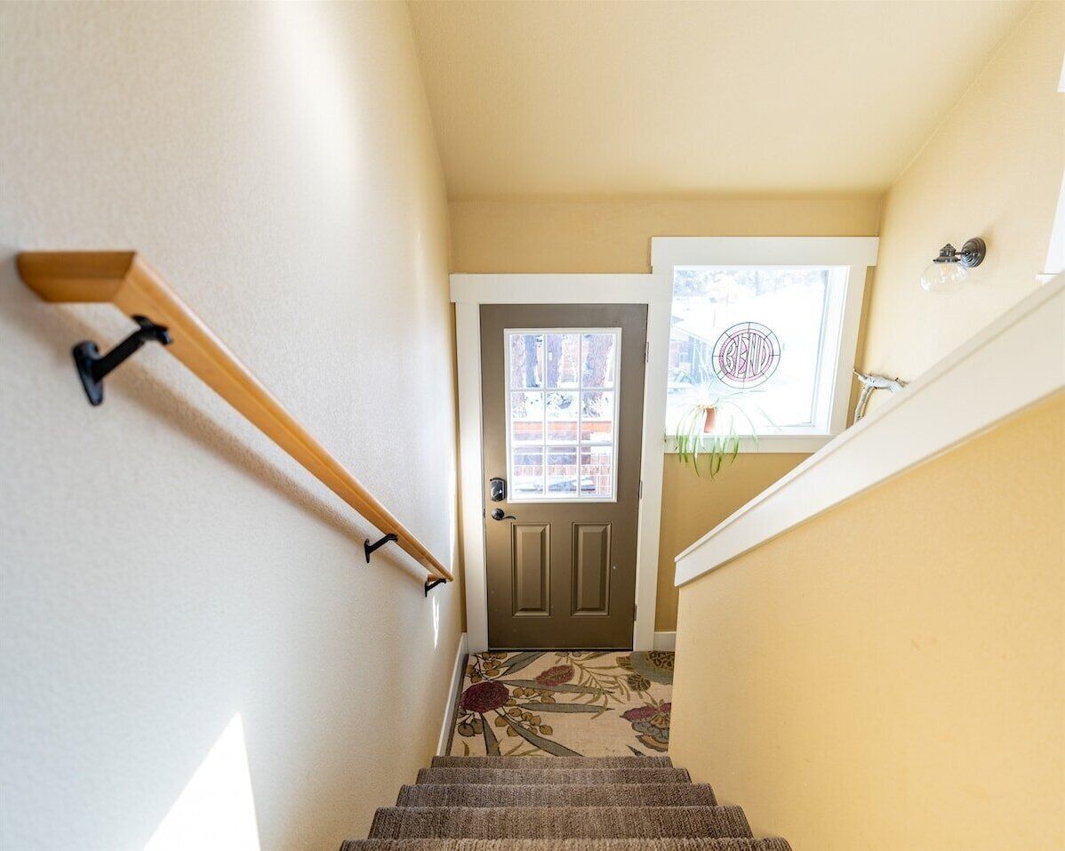 Un escalier avec une rampe en bois menant à une porte dotée d’une fenêtre.