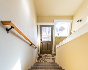 Staircase leads to a door with a window above, featuring a handrail and carpeted steps.