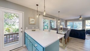 A kitchen with a central island, pendant lights, and a view of the outdoors. - Wonderfully Decorated Two Bedroom Water Oak Villa! (Hilton Head)
