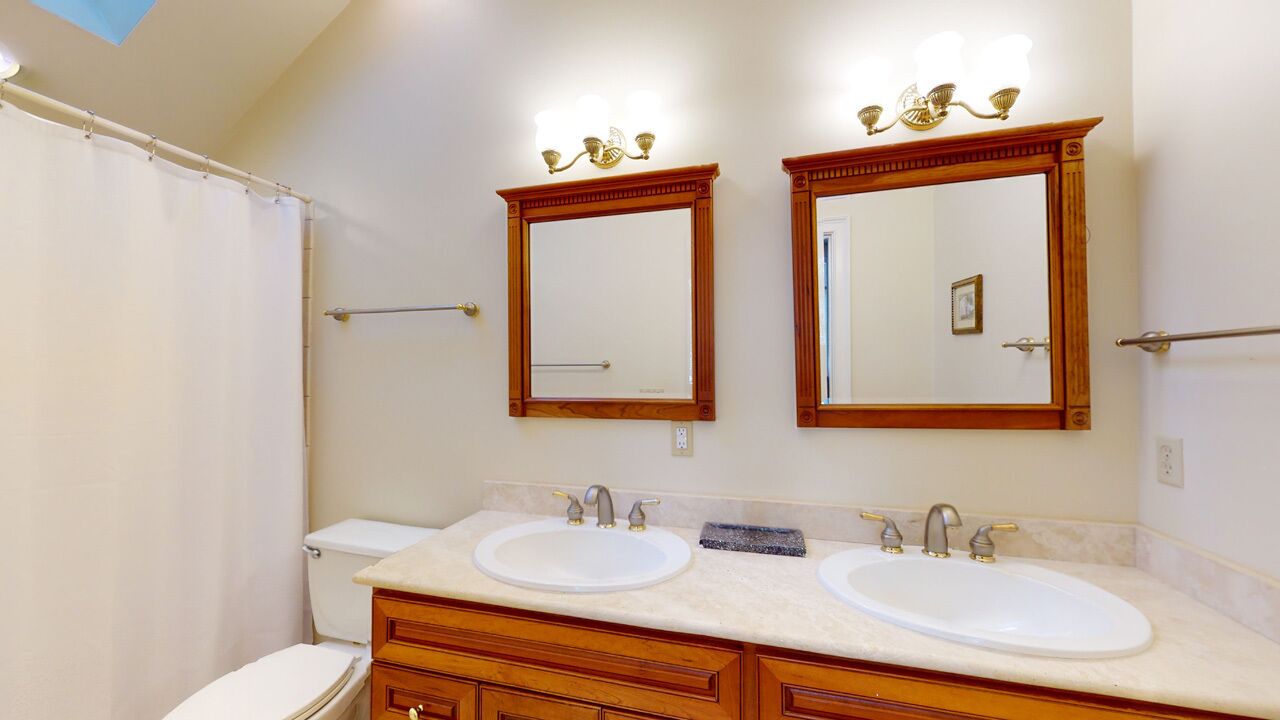 A bathroom with two sinks, a toilet, and a shower curtain.