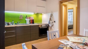 Eine moderne Küche mit grüner Rückwand, Edelstahlgeräten und einem Essbereich mit Tisch für zwei Personen.