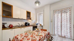 Eine Küche mit Esstisch, Schränken und einem Fenster mit Vorhängen.