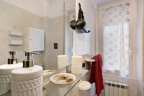 Une salle de bain avec deux lavabos, un miroir, un porte-serviettes et une fenêtre avec un rideau.