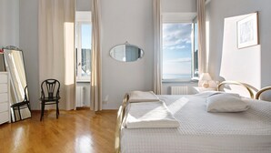 Een slaapkamer met een bed, een stoel, een spiegel, een raam en een radiator.