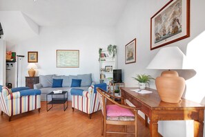 A living room with a sofa, striped chairs, a wooden table, and a large vase.