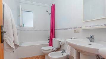 Un baño con inodoro, bidé, bañera y lavamanos.