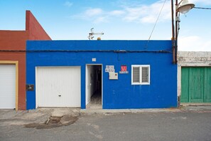 Un edificio con fachada azul, puerta de garaje blanca y puerta verde.