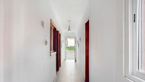 A hallway with white walls, wooden doors, and a tiled floor.
