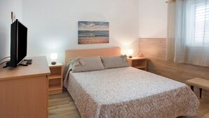 A bedroom with a bed, bedside tables, a TV, and a painting on the wall.