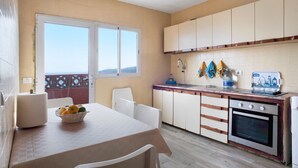 A kitchen with a dining table, chairs, a basket of fruit, a water dispenser, and an oven.