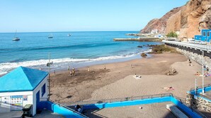 Uma praia com uma torre de salva-vidas, um píer e barcos na água.