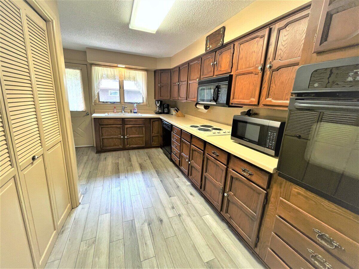 A compact kitchen with wooden cabinets, a microwave, and a refrigerator.