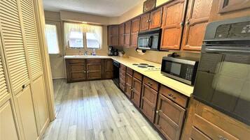 A compact kitchen with wooden cabinets, a microwave, and a refrigerator.