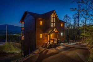 A two-story log cabin with a central staircase, large windows, and a porch. - Free Attractions! Private Indoor Heated Pool, Hot Tub, Great Views, Games (Gatlinburg)