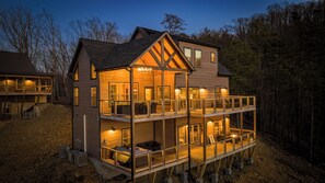 A two-story wooden house with a balcony, multiple windows, and a fireplace.