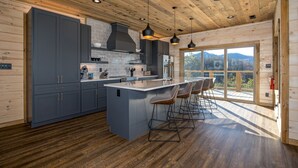 Uma cozinha moderna com uma ilha grande, banquetas e vista para o exterior.