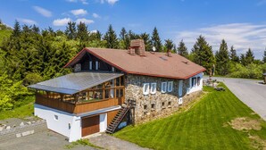 A modern house with a stone facade, a wooden deck, and a large garage. - Chata Ještědka (Svetla pod Jestedem)