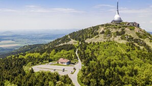 A mountain lodge with a large conical tower, surrounded by dense forest and a clear sky. - Chata Ještědka (Svetla pod Jestedem)