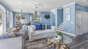 A spacious living area with a sofa, a glass coffee table, and a ceiling fan. - Beachfront with Bikes, In-House Gym and LSV (Santa Rosa Beach)