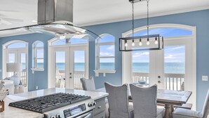 A kitchen with a gas stove, oven, and a view of the ocean through large windows. - Beachfront with Bikes, In-House Gym and LSV (Santa Rosa Beach)
