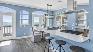 A kitchen with a large island, bar stools, and a view of the ocean through the windows. - Beachfront with Bikes, In-House Gym and LSV (Santa Rosa Beach)