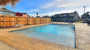A rectangular swimming pool with a wooden fence and a concrete deck. - Lemon Chill Home, Arcade, Pool & Near Beach (Port Aransas)