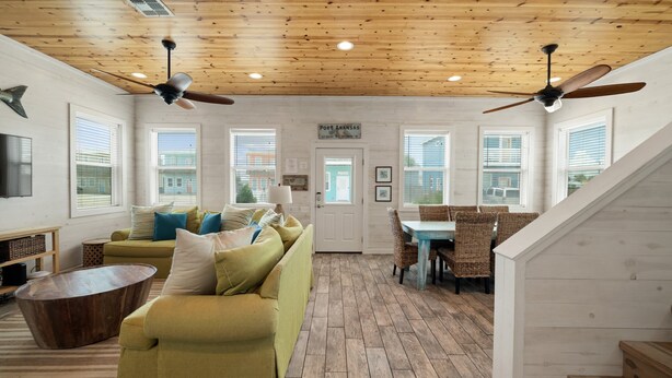 A spacious living room with a wooden ceiling, a sofa set, a dining table with chairs, and a staircase. - Lemon Chill Home, Arcade, Pool & Near Beach (Port Aransas)