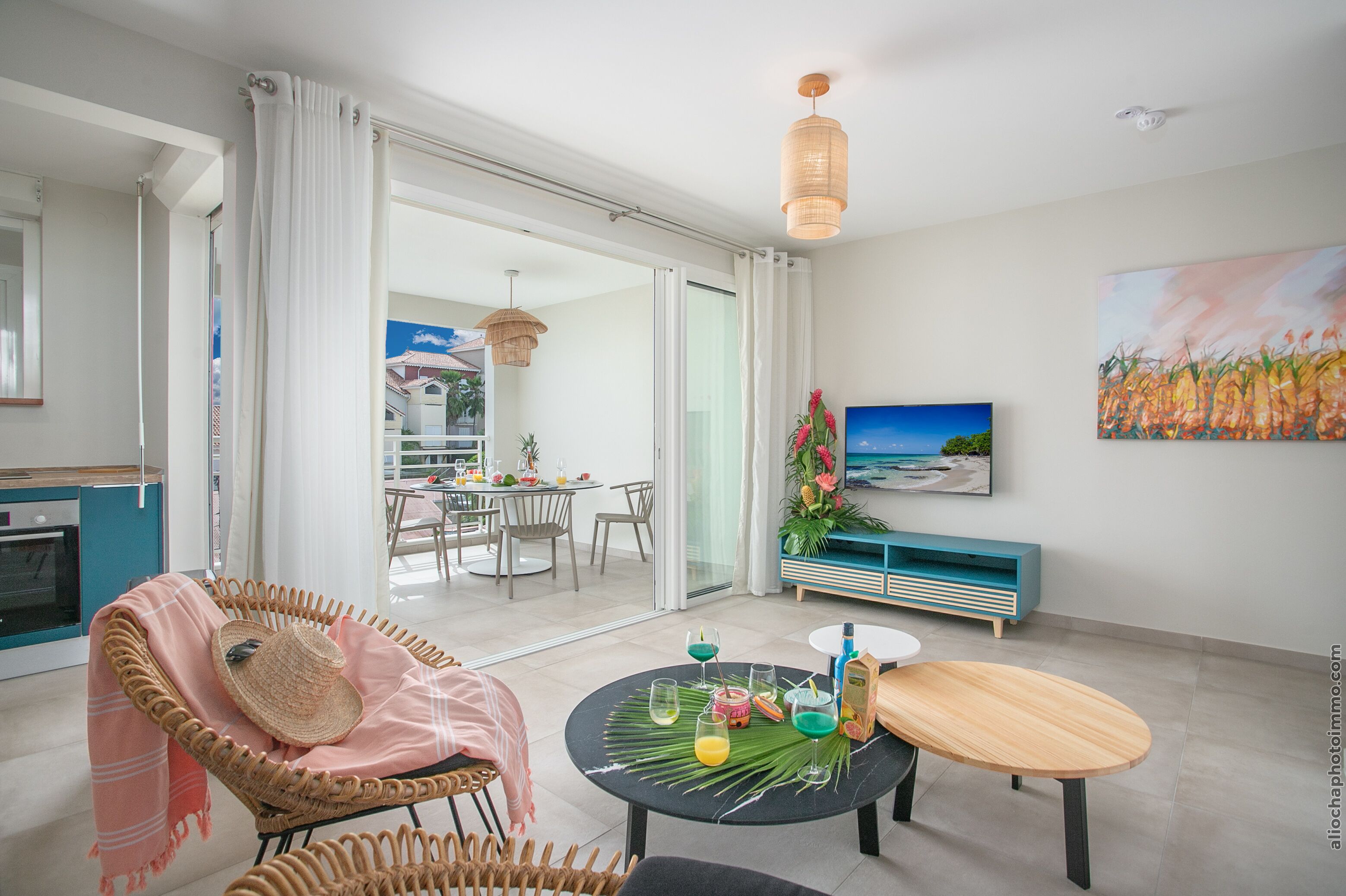 A modern living room with a dining area, a large window, and a painting on the wall.