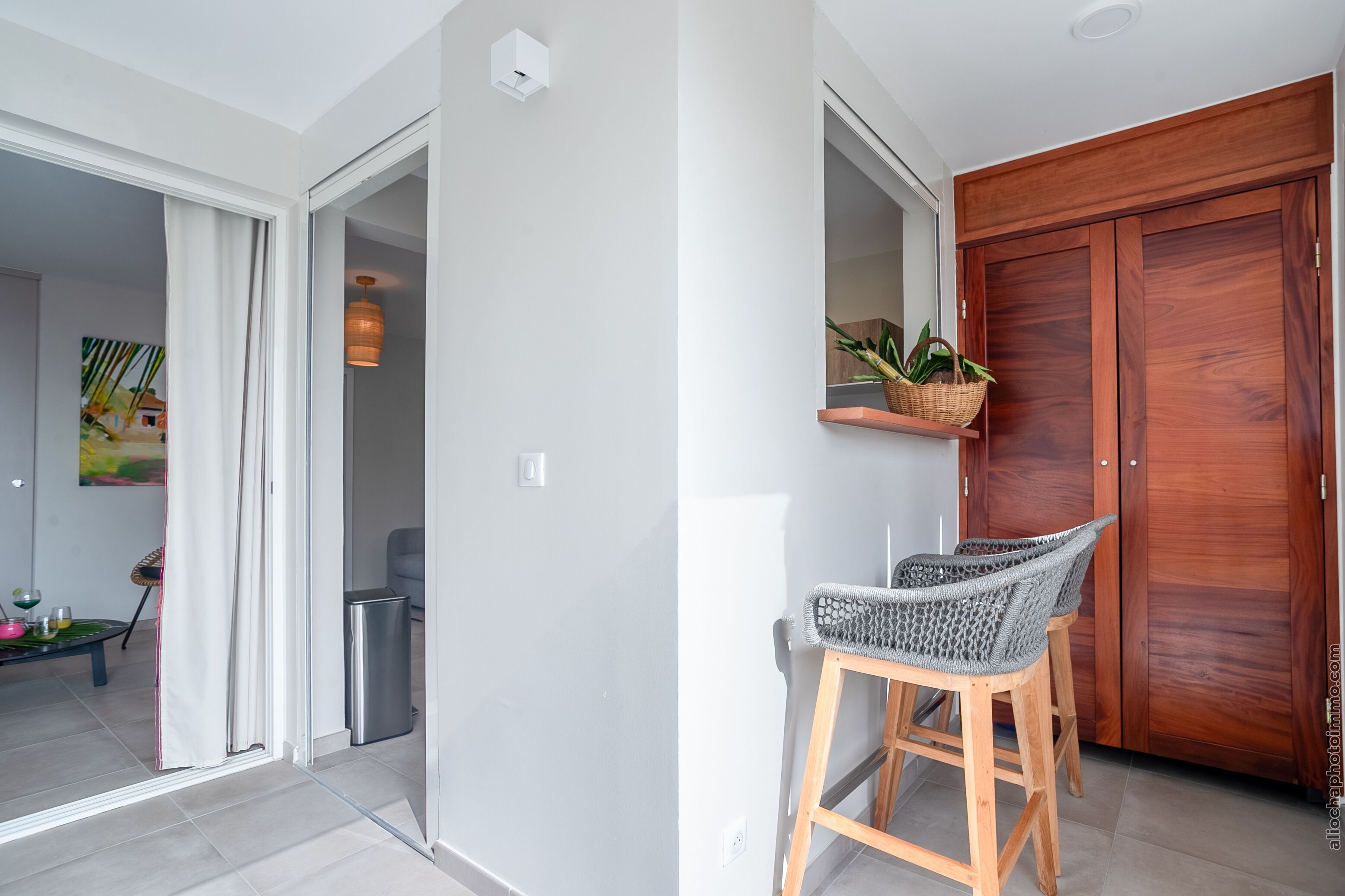 Una cocina moderna con una puerta de madera, un pequeño estante con plantas y dos sillas de mimbre.