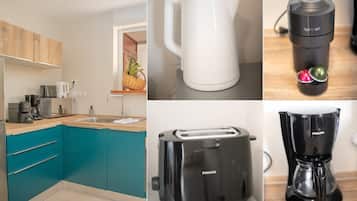 A modern kitchen with teal cabinets, a white kettle, a black coffee maker, a toaster, and a blender.