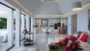 A modern living room with a white sofa, a coffee table, and a dining area with white chairs. - Stellae (1/6 Rooms) Luxury villa (Anse de Lorient)